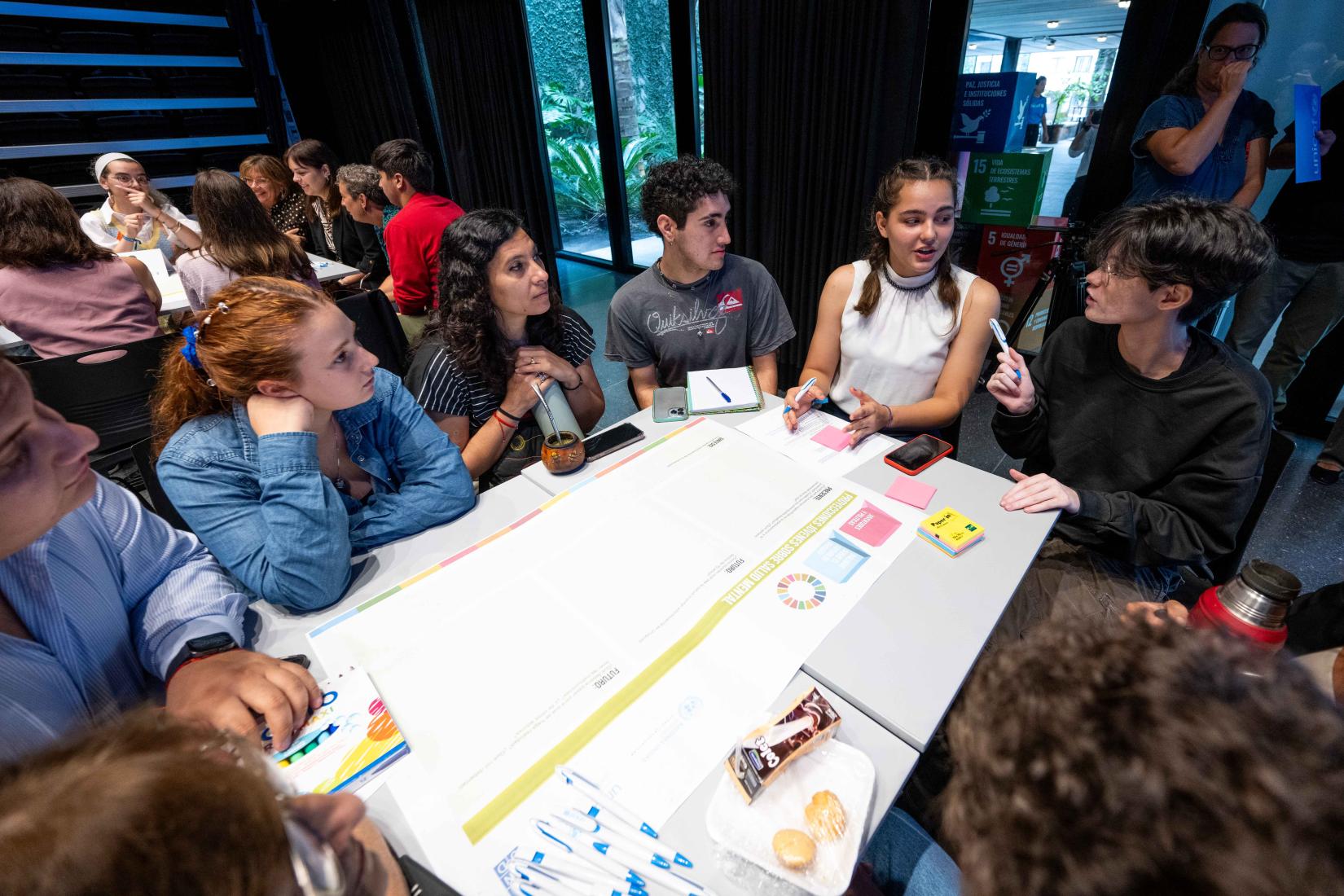 Jovenes conversando en una de las mesas dispuestas en el evento. 