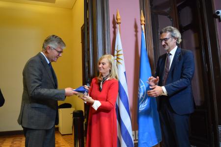 La vicepresidenta Beatríz Argimón entrega el Pabellón Nacional a Jean Pierre Lacroix, Secretario General Adjunto de Operaciones de Paz, durante la ceremonia de inauguración de la Casa ONU.