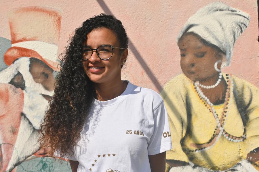 Mujer afro con mural detrás. 